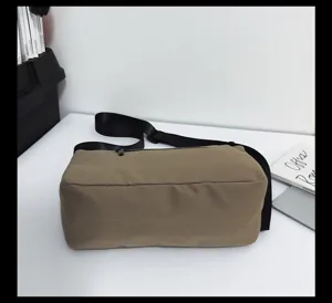 Khaki canvas crossbody tas detailweergave, duurzame stof met zwarte schouderriem.