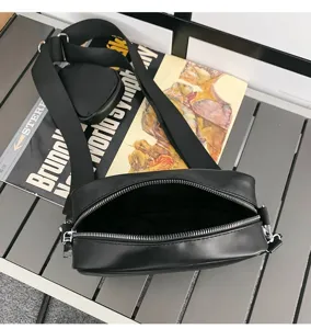 Detail zwarte crossbody schoudertas, stijlvolle brede riem met mini pouch, casual design.