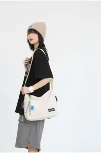 Detail shot of the casual canvas messenger bag showing utility strap, label, and design.