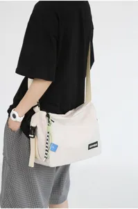 Detail view of the casual canvas crossbody bag in beige, showing the adjustable strap and tag.