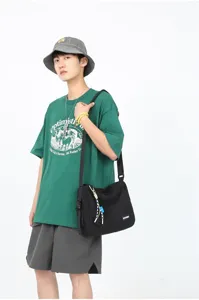 Close-up scene of a casual black canvas messenger bag worn by a model, showcasing style.