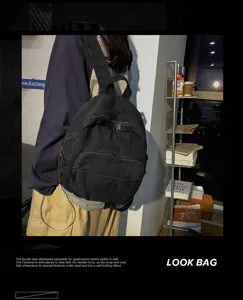 Black canvas backpack detail view showcasing durable fabric, dual zippers and handy front pocket.