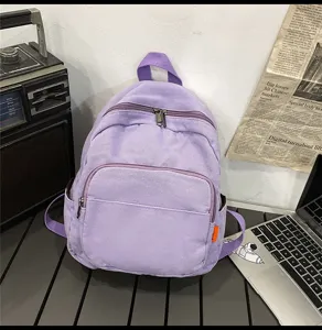 Purple canvas backpack detail showing dual zippers, front pocket and side storage design.