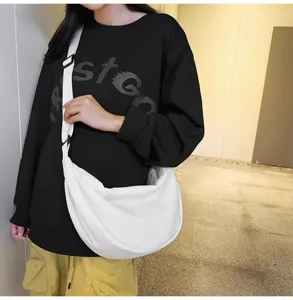 Detailed view of a casual large capacity solid color dumpling crossbody bag worn by model.