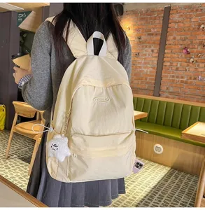 Detail view of the stylish light yellow casual backpack worn by a student in a cozy cafe.