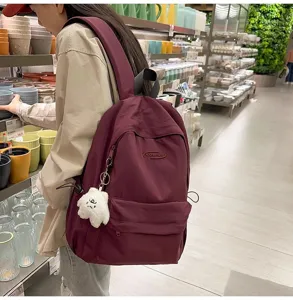 Casual burgundy backpack for daily school travel, featuring front pocket and cute plush charm.