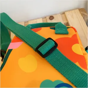 Canvas crossbody bag with vibrant floral pattern and green adjustable strap detail view.