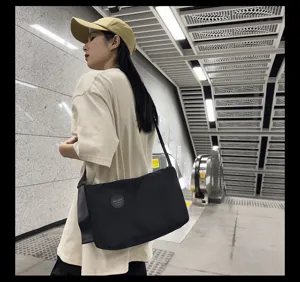 Gedetailleerd overzicht van de zwarte canvas schoudertas gedragen in het metrostation.