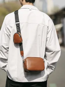 Klassieke bruine lederen crossbodytas met klein zakje op de riem voor dagelijks gebruik onderweg.