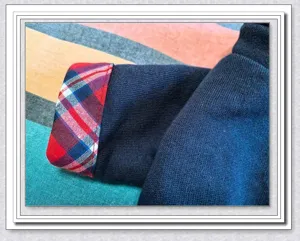 Close up view of pet dog clothes sleeve cuff featuring dark blue knit and plaid lining.