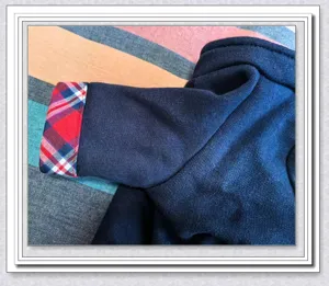 Close up detail of pet dog winter thick warm plush cardigan sleeve with red plaid cuff lining.