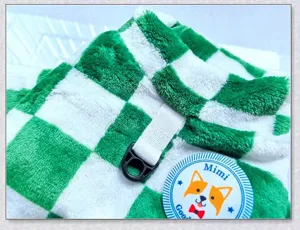 Close-up detail of green and white checkered pet fleece clothing with D-ring harness strap.