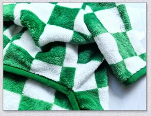 Green white checkerboard pet fleece coat detail, warm four-leg dog winter clothing.