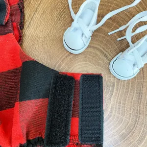 Dettaglio vestito per animali a quadri rossi e neri con mini scarpe bianche e cinturino velcro.