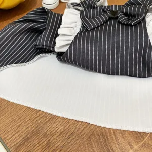 Dettaglio ravvicinato di vestito per animali a righe bianche e nere con fiocco e balze.