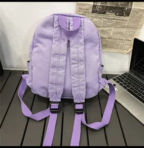Purple canvas backpack detail view, showing adjustable straps and solid color design.