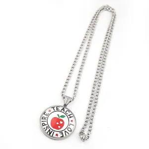 Gros plan détail du collier pendentif pomme enseignant avec texte inspirant et chaine.