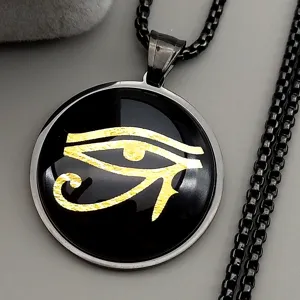 Closeup of stainless steel Eye of Horus pendant necklace with gold symbol detailing.