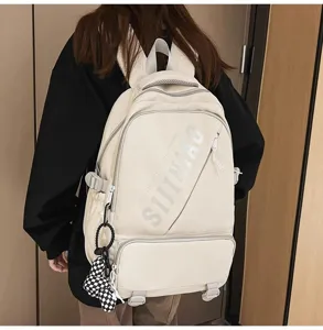 Nahaufnahme des modischen Campus-Rucksacks mit Fronttasche, Buchstaben-Print und charmantem Anhänger.