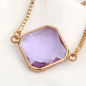 Close-up detail of a minimalist gold-plated box chain bracelet with a square purple crystal.