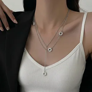 Collier argenté minimaliste à double couche avec pendentifs ronds et charme lettre.