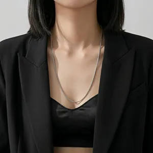 Vue détaillée d'un collier chaîne serpent argenté minimaliste porté par un mannequin.