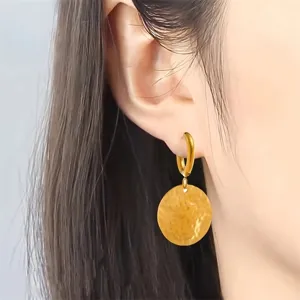 Close-up detail of stylish gold stainless steel hammered disc pendant hoop earrings for women.