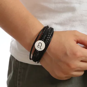 Close-up view of men's multi-layer braided leather bracelet featuring a metal zodiac sign charm.