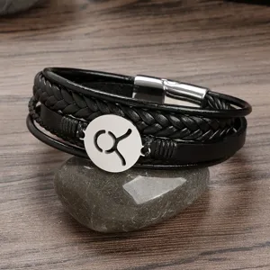 Close-up of men's black braided leather bracelet with stainless steel Taurus zodiac charm.