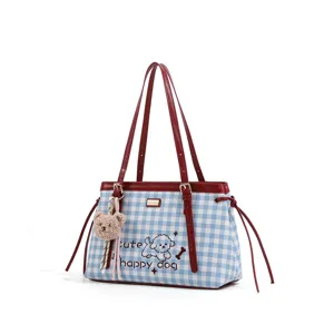 Bolso de hombro de cuadros azul y blanco con asas de cuero rojo y colgante de oso de peluche.