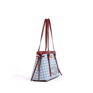 Detalle del bolso de cuadros vichy azul y blanco con correas de cuero rojo y estampado de cachorro.