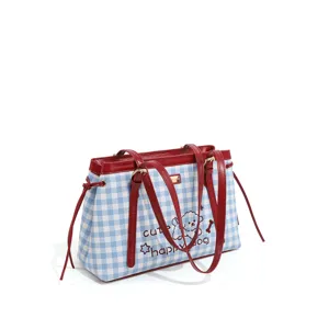 Primer plano detallado de la bolsa a cuadros azules y blancos con asas de cuero rojo.