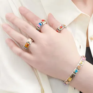 Close-up view of stainless steel modular charm bracelet and colorful rings set for daily wear.
