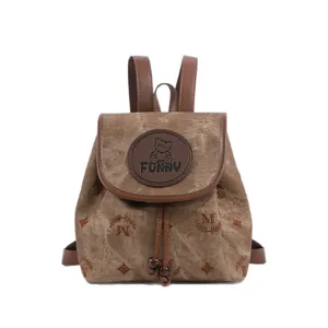 Detail van bruine canvas vintage rugzak met monogram print, lederen bandjes en leuke beren patch.