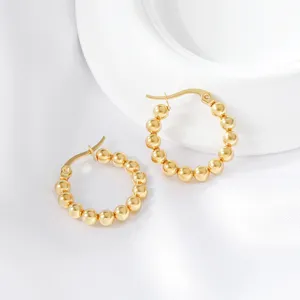 Close-up of elegant gold-plated stainless steel beaded hoop earrings, modern detail shot.