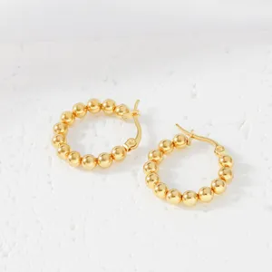 Detailed close-up of gold beaded hoop earrings showing the delicate ball chain link design.