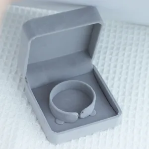 Detail van grijze fluwelen sieradendoos, elegante ring en armband geschenkverpakking.