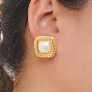 Close-up detail of geometric square gold pearl stud earrings worn on ear, elegant jewelry.