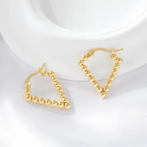 Close-up detail of trendy gold-plated beaded triangle hoop earrings, elegant stainless steel jewelry.