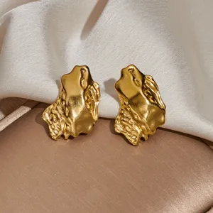 Gold irregular metal earrings detail closeup view showcasing unique textured surface design.