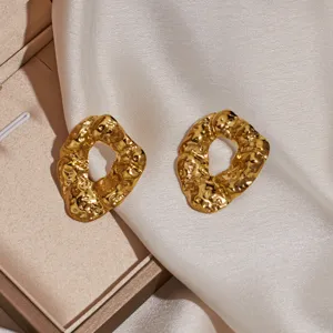 Close-up detail of irregular hammered gold earrings showing unique metallic texture and finish.