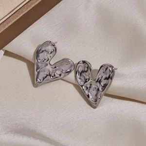 Metallic irregular heart stud earrings detail view, showing unique textured design and glossy finish.