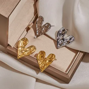 Detail shot of irregular metal heart earrings in gold and silver, stylish stainless steel.