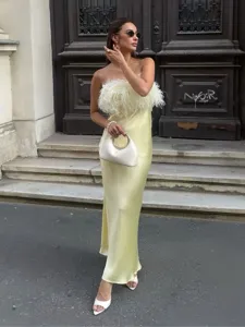 Detailed view of elegant strapless satin long dress with fluffy feather bust design in soft yellow.