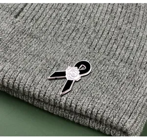 Graue Strickmütze mit schwarzer Schleife und weißer Rosen-Emaille-Brosche für den täglichen Look