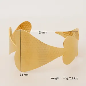 Detail shot of the wide gold cuff bracelet showcasing intricate clover cutout pattern and specs.
