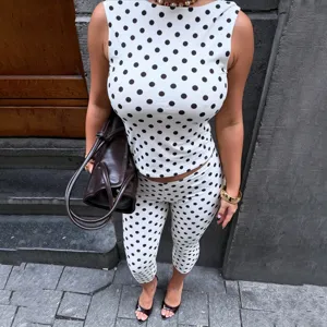 Detailopname van de mouwloze top met zwarte stippen en de bijpassende cropped broek in stijl.