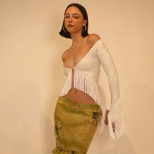 Vue détaillée du haut court sexy avec franges et manches longues et de la jupe verte midi.