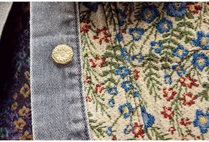 Nahaufnahme der Damen Vintage Blumen Jacquard und Jeans Patchwork Jacke mit Metallknopf.