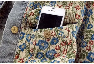 Frühlings florale Brokat Jeansjacke Detailansicht mit Brusttasche und Metallknöpfen.